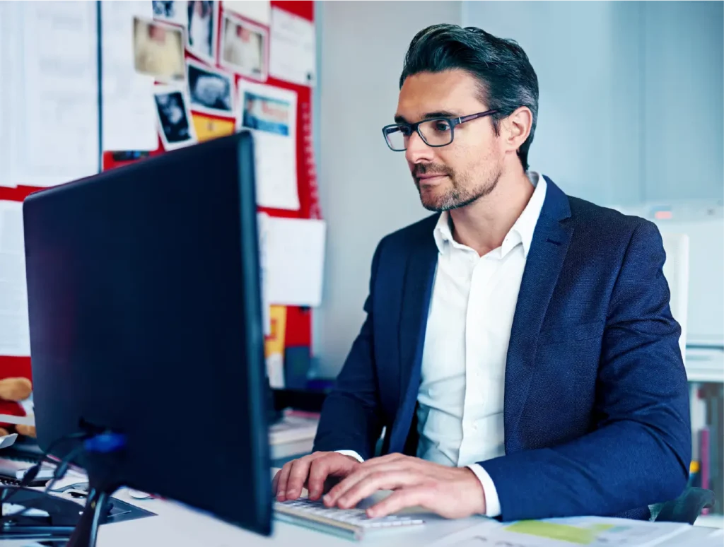 Professional software developer at Realized Solutions focused on a computer monitor in a productive office environment.