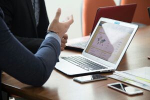 Business professional analyzing dashboard metrics and performance reports on a laptop during a strategy meeting.