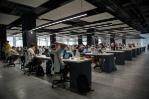 Technology professionals working on laptops and computers in a modern open office, showcasing collaboration, digital workspaces, and business productivity.