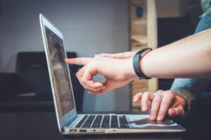 IT support professional assisting a colleague at a laptop, demonstrating software troubleshooting, technical guidance, and workplace collaboration.