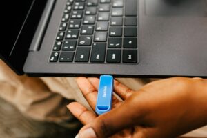 Person connecting a USB flash drive to a laptop for file storage, data transfer, backup, and information management.