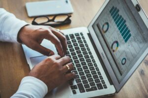 Professional analyzing business metrics and performance dashboards on a laptop, representing business intelligence, data analytics, reporting, and strategic planning.